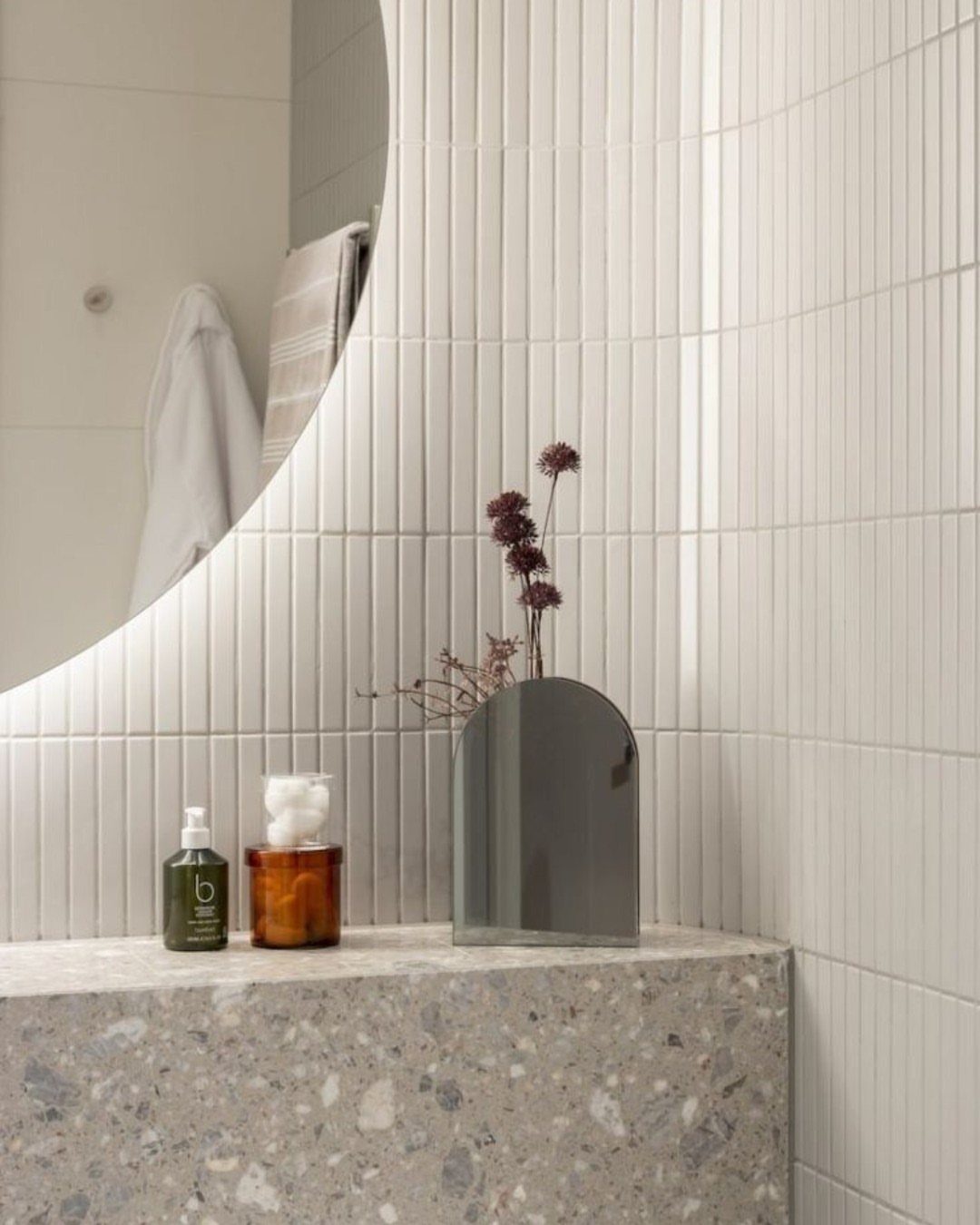 White KitKat porcelain mosaic tiles on a bathroom wall behind a stone countertop.